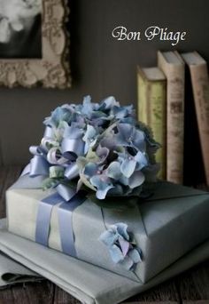 a stack of wrapped presents sitting on top of a wooden table next to books and pictures