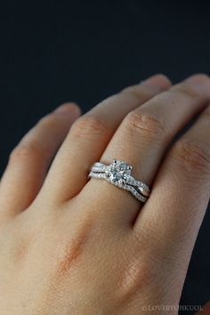 a woman's hand with a wedding ring on her left hand and two diamonds on the middle finger