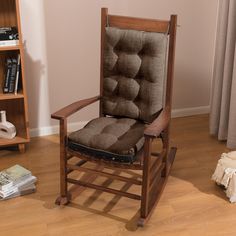 a brown rocking chair sitting on top of a hard wood floor next to a book shelf