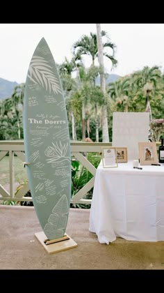 there is a surfboard on the table with pictures and wine bottles next to it