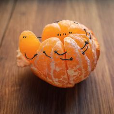 an orange with faces drawn on it sitting on top of a wooden table next to a quote