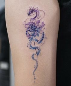 a woman's arm with a tattoo on it that has flowers and a snake