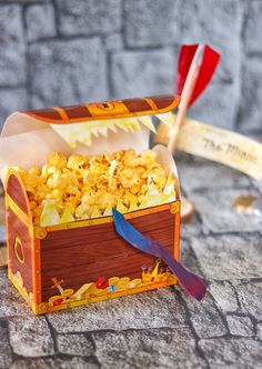 a wooden box filled with popcorn sitting on top of a stone floor next to a toothbrush