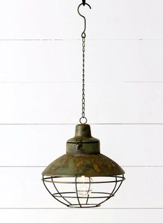 an old - fashioned light fixture hangs from a chain on a white wooden wall with planks in the background