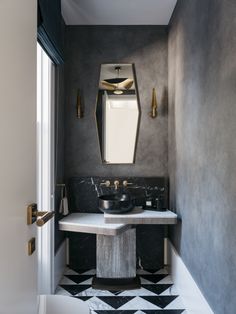 a bathroom with black and white tile flooring, gold fixtures and a marble sink