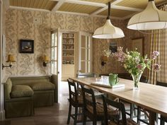 a dining room table with chairs and flowers in vases on the top of it