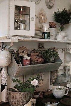 an old fashioned kitchen with lots of pots and pans on the shelf above it