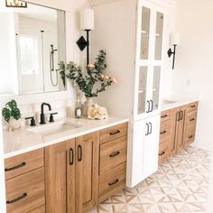 a bathroom with two sinks, cabinets and flowers in vases on the counter top