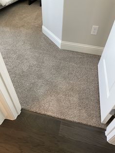 an open door leading to a bedroom with a bed in the background and carpet on the floor