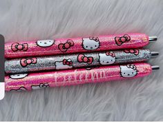 three hello kitty pens with glitter on them