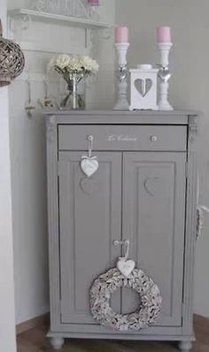 a grey cabinet with a wreath and two candles