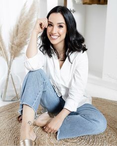 a woman is sitting on the floor smiling