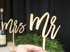 a person holding a wooden cake topper with the word mr and mrs on it