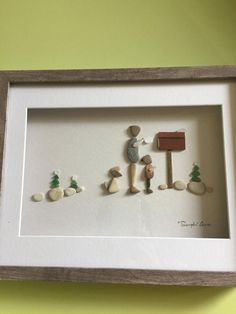 a white frame with some miniature people and trees on it in front of a green wall