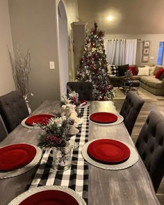 a dining room table set for christmas with red plates and placemats on it