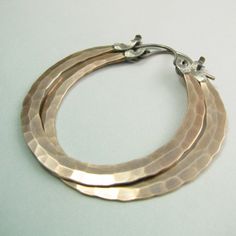 "The ultimate large bronze and sterling silver hoop earrings. Our new bronze ( also known as red brass and nugold ) Rio design, meticulously and deftly forged for a polished but rustic look. Finished with our sterling silver latch design for a secure and easy to use closure that maintains a sleek profile. A dynamic pair of handmade hammered hoops that are sure to become a favorite addition to your jewelry collection. Oxidized, brushed and polished to finish. Rio Hoops are a signature Mocahete de Hammered Copper Hoop Jewelry, Hammered Copper Round Hoop Earrings, Small Bronze Metal Hoop Earrings, Hammered Rose Gold Sterling Silver Hoop Earrings, Rose Gold Hammered Sterling Silver Hoop Earrings, Electroformed Metal Hoop Earrings, Electroformed Brass Hoop Earrings, Artisan Electroformed Hoop Earrings, Small Copper Hoop Jewelry, Hammered