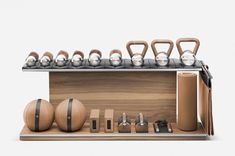 an assortment of kettles, balls and other items on a wooden stand with a white background