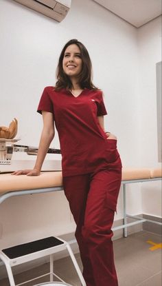 a woman in red scrubs standing next to a counter