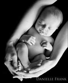 a black and white photo of a baby being held by its mother's hands