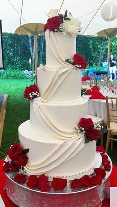 a three tiered wedding cake with red and white flowers