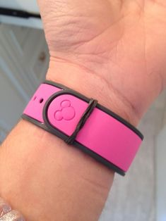 a pink wristband with a mickey mouse on it's side and a black band around the wrist