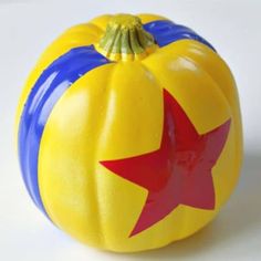 a yellow and blue pumpkin with a red star on it's top sitting on a white surface