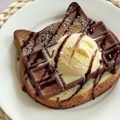 a white plate topped with waffles covered in chocolate syrup and ice cream next to a woven basket