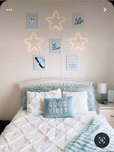 a bed with white sheets and blue pillows in a room decorated with star decorations on the wall