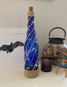 a blue glass bottle sitting on top of a table next to a vase and candle