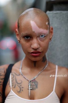 a woman with shaved hair and piercings on her head is looking at the camera