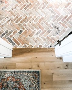 an area rug on the floor in front of a brick wall and white door frame