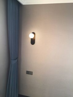 an empty room with a lamp on the wall and curtains hanging from the ceiling in front of it