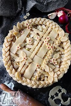 a pie sitting on top of a wooden table next to other food and utensils