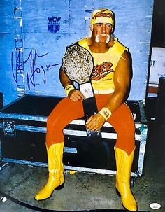 a man sitting on top of a trunk holding a wrestling ring and wearing yellow boots