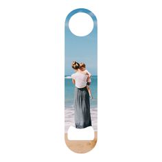 a bottle opener with an image of two women hugging on the beach in front of the ocean