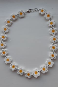 a white and yellow necklace with flowers on it