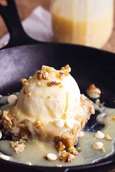 an ice cream sundae in a skillet with nuts on the rim and toppings