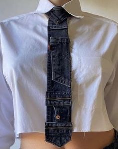 a person wearing a white shirt and tie with blue jeans on their waist, standing in front of a wall