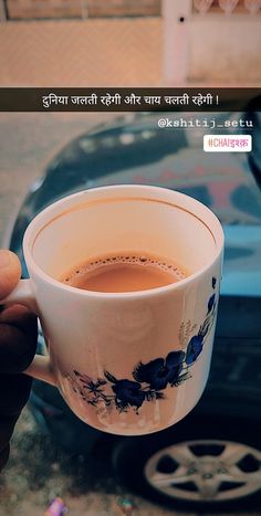 a person holding a cup of coffee in front of a blue car with the caption on it