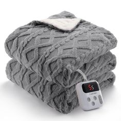 an alarm clock is sitting on top of a pile of gray blankets and blanketes