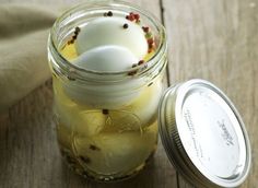 a jar filled with some kind of food on top of a wooden table next to a spoon