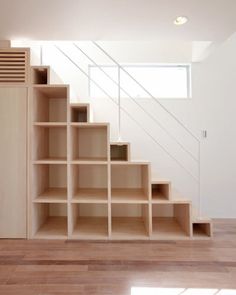 an empty room with some shelves on the wall and stairs to the second floor in it