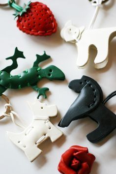 several different types of animal shaped key chains on a white surface with strawberries and other items in the background