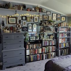 a bedroom with many bookshelves and pictures on the wall