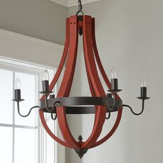 a wooden chandelier with candles hanging from it's sides in front of a window