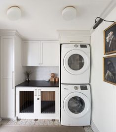 a washer and dryer sitting in a kitchen next to each other with pictures on the wall