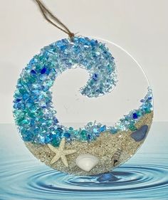 a glass ornament with blue and white beads in the shape of a letter