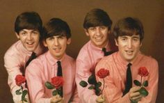 three men in pink shirts and ties holding roses