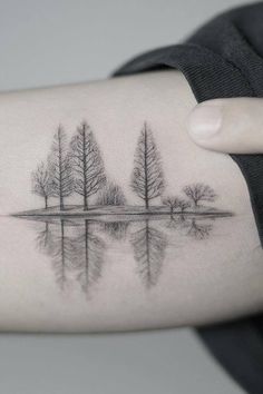 a woman's arm with trees and water on it