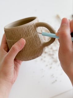 a person is holding a cup with a toothbrush in it and writing on the side